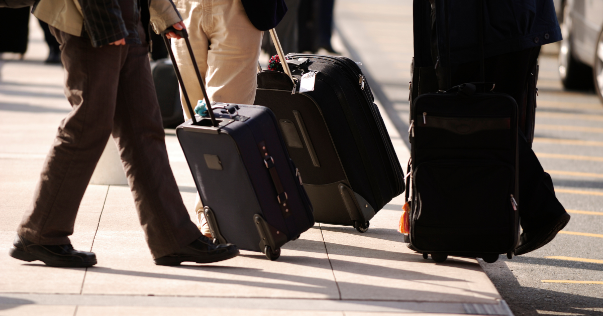 Person pushing luggage down street