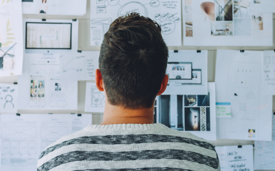 Man looking at cork board of project plans