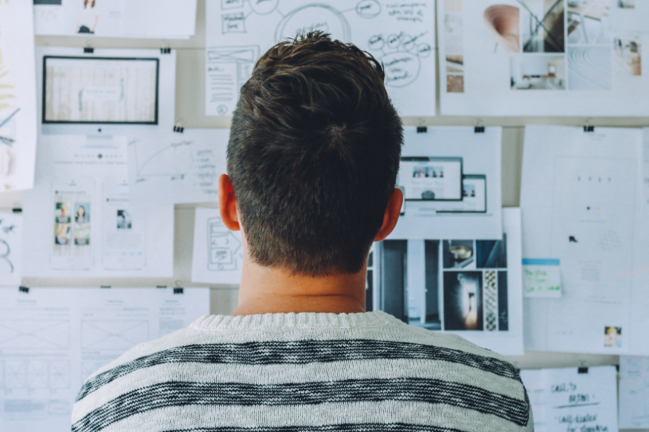 Man looking at cork board of project plans