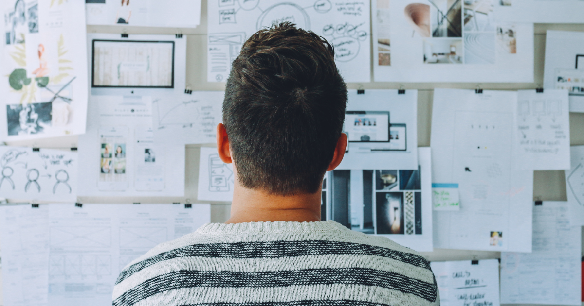 Man looking at cork board of project plans