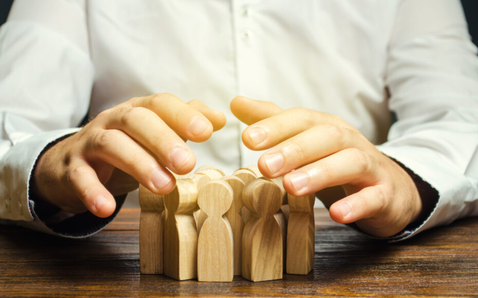 Person with wooden blocks shaped as people - Concept of Human Resource Management