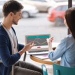 People having conversation outside on laptop