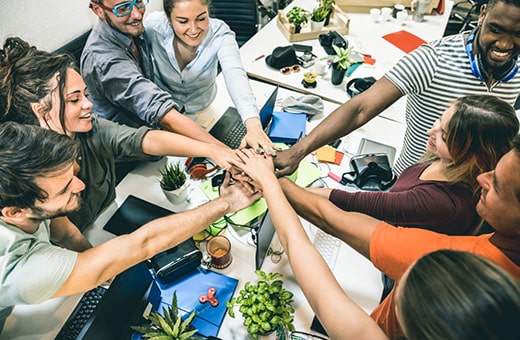 Group of happy employees putting hands together