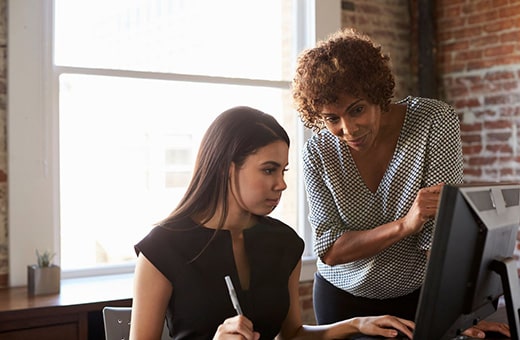 Two business women discussing HR technology on computer