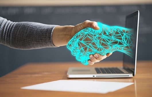 Person shaking hands with virtual hand coming out of laptop